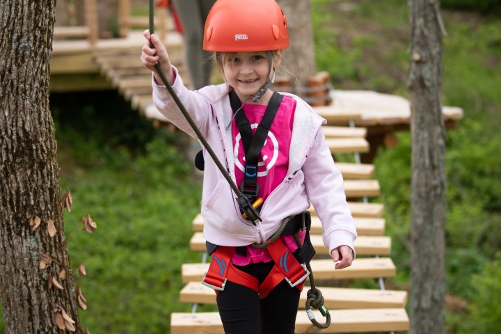 a little girl riding on top of a wooden fence